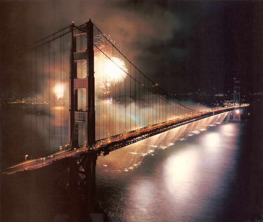 Fireworks bursting over the Golden Gate Bridge at night during The Golden Dream, the bridge's 50th anniversary celebration